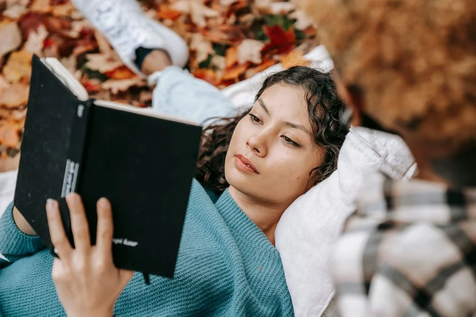 A woman resting in a park reading a book, relaxed and unhurried