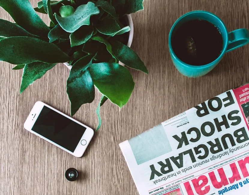 A phone resting face-down on a wooden table during a quiet morning