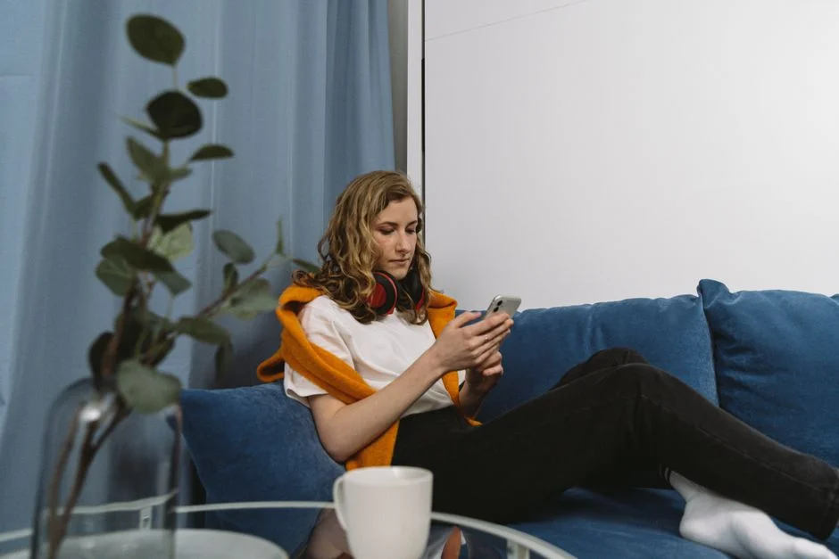A woman scrolling on her phone while sitting on a couch