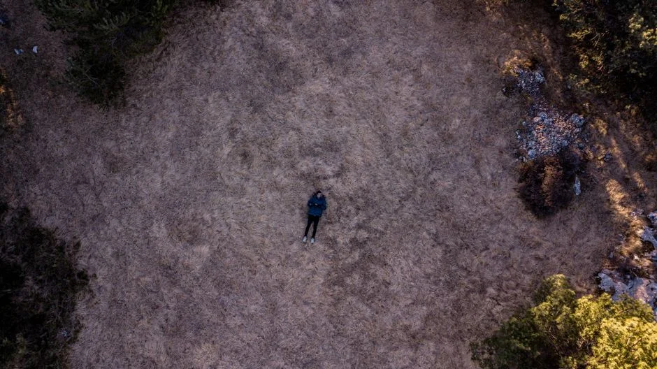 An aerial view of a person lying still in an open field