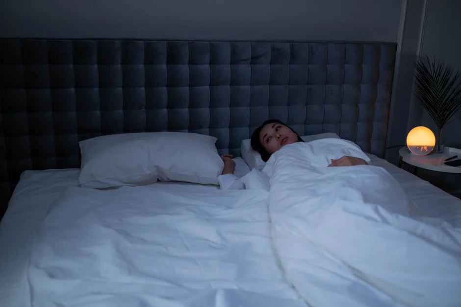 Woman lying awake in a dark bedroom at night, looking up while unable to sleep