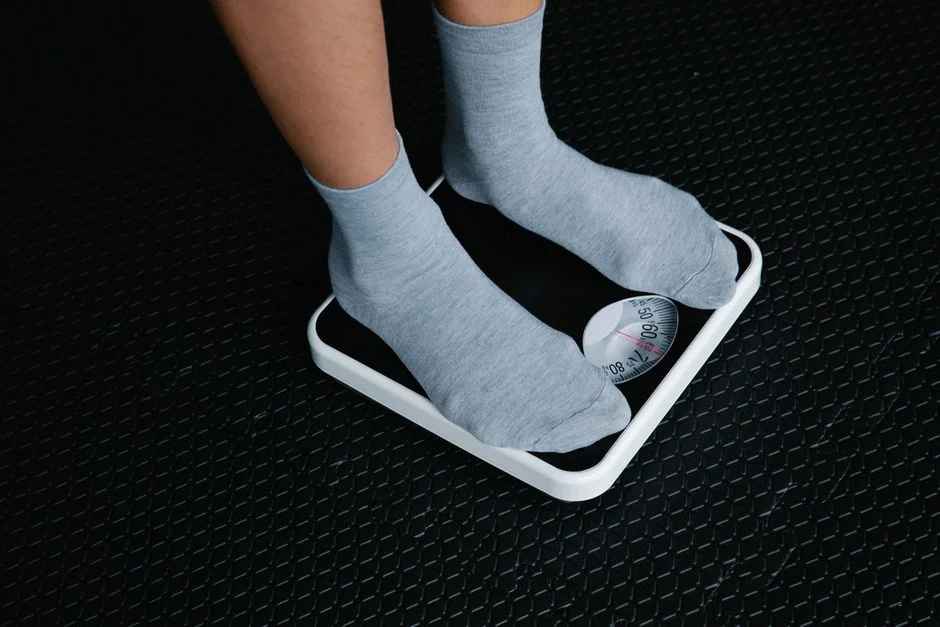 Person in gray socks standing on a white bathroom scale
