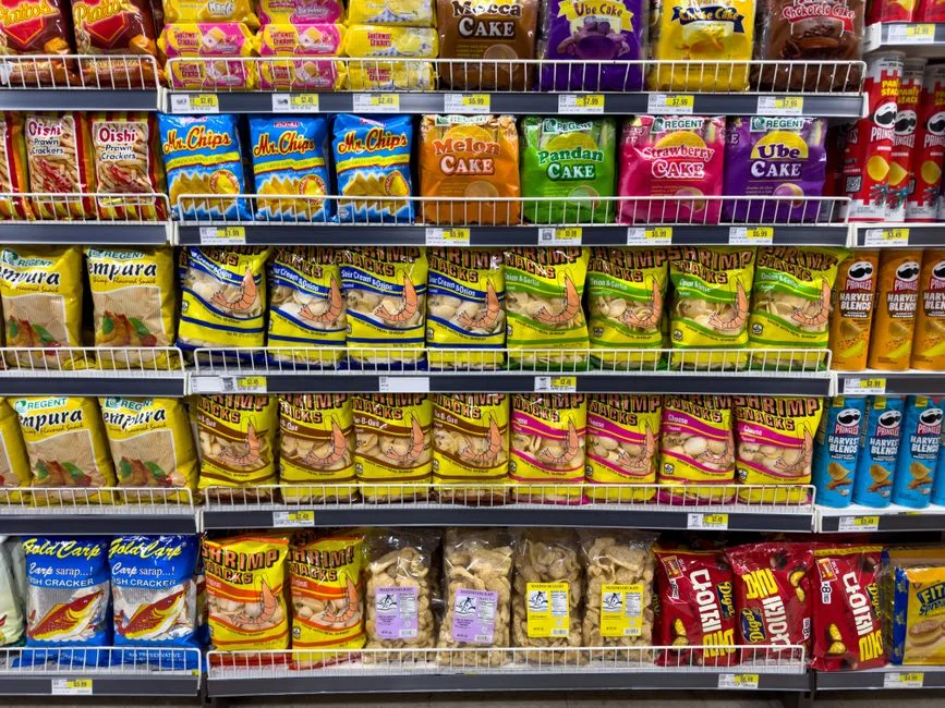 Supermarket shelves stacked with brightly packaged chips, crackers, cakes and other ultra-processed snacks