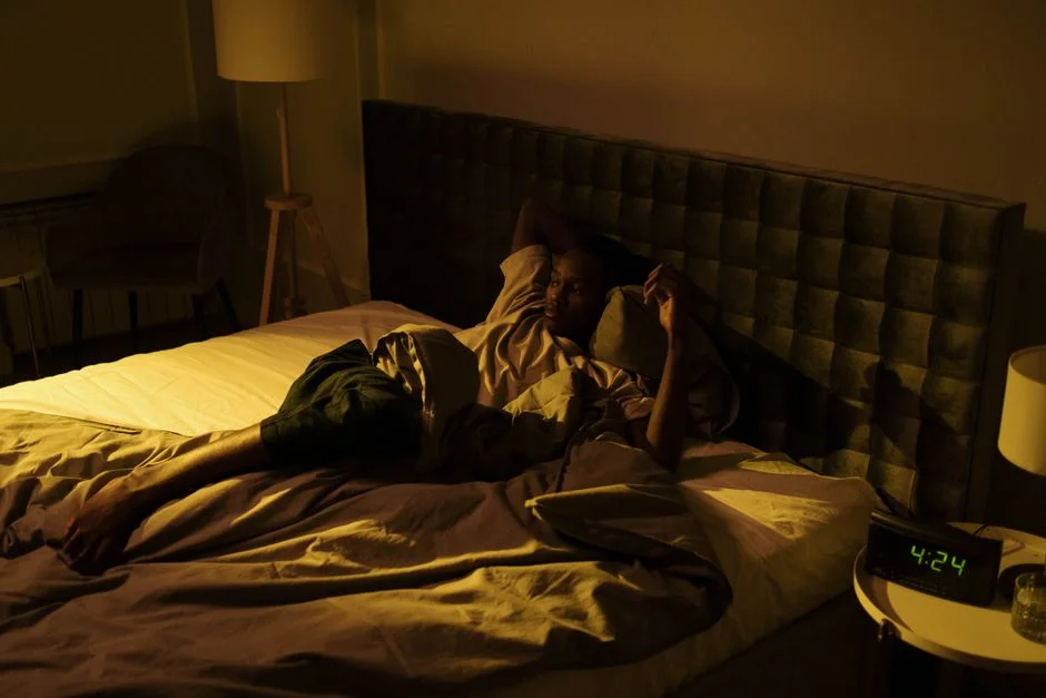 Man lying awake in bed at night with eyes open