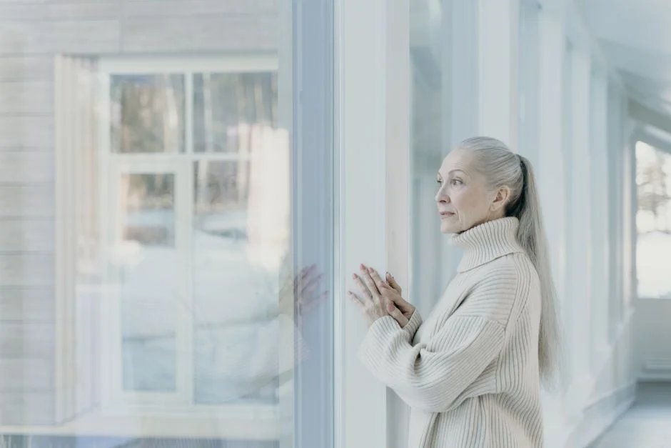 Older woman looking out a window in soft light