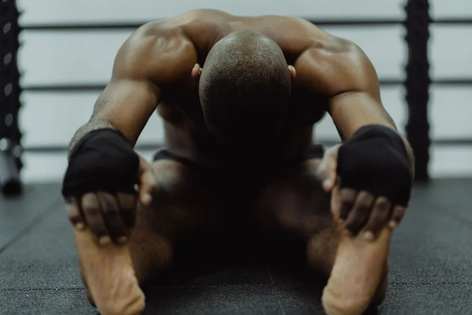 Man stretching and holding his feet while seated on the floor