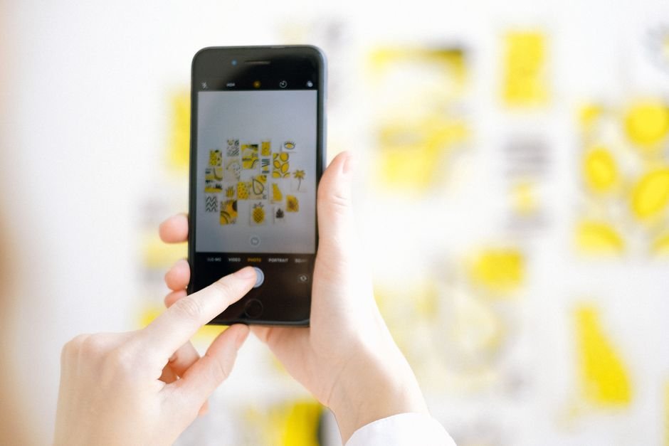 Close-up of a hand holding a smartphone to photograph artwork